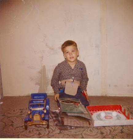 Me at 5 years old with Christmas presents of a car, a gun and holster set, and a ping-pong type game